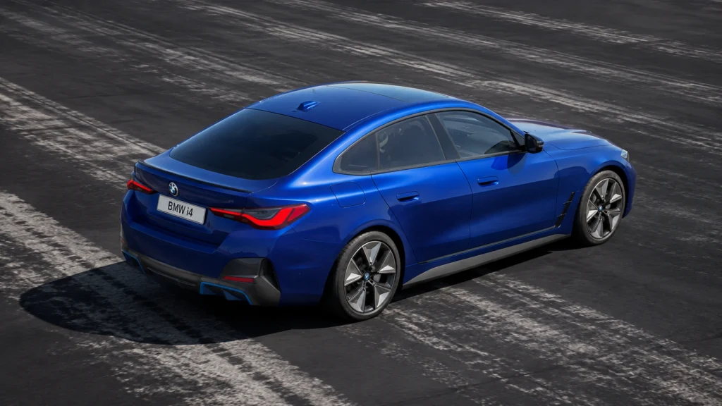 Blue BMW i4 electric sedan shown from the rear on a city road.