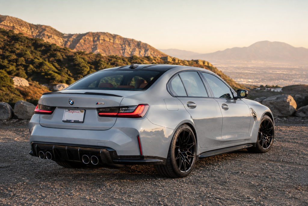 Gray BMW M3 rear three-quarter view in mountains